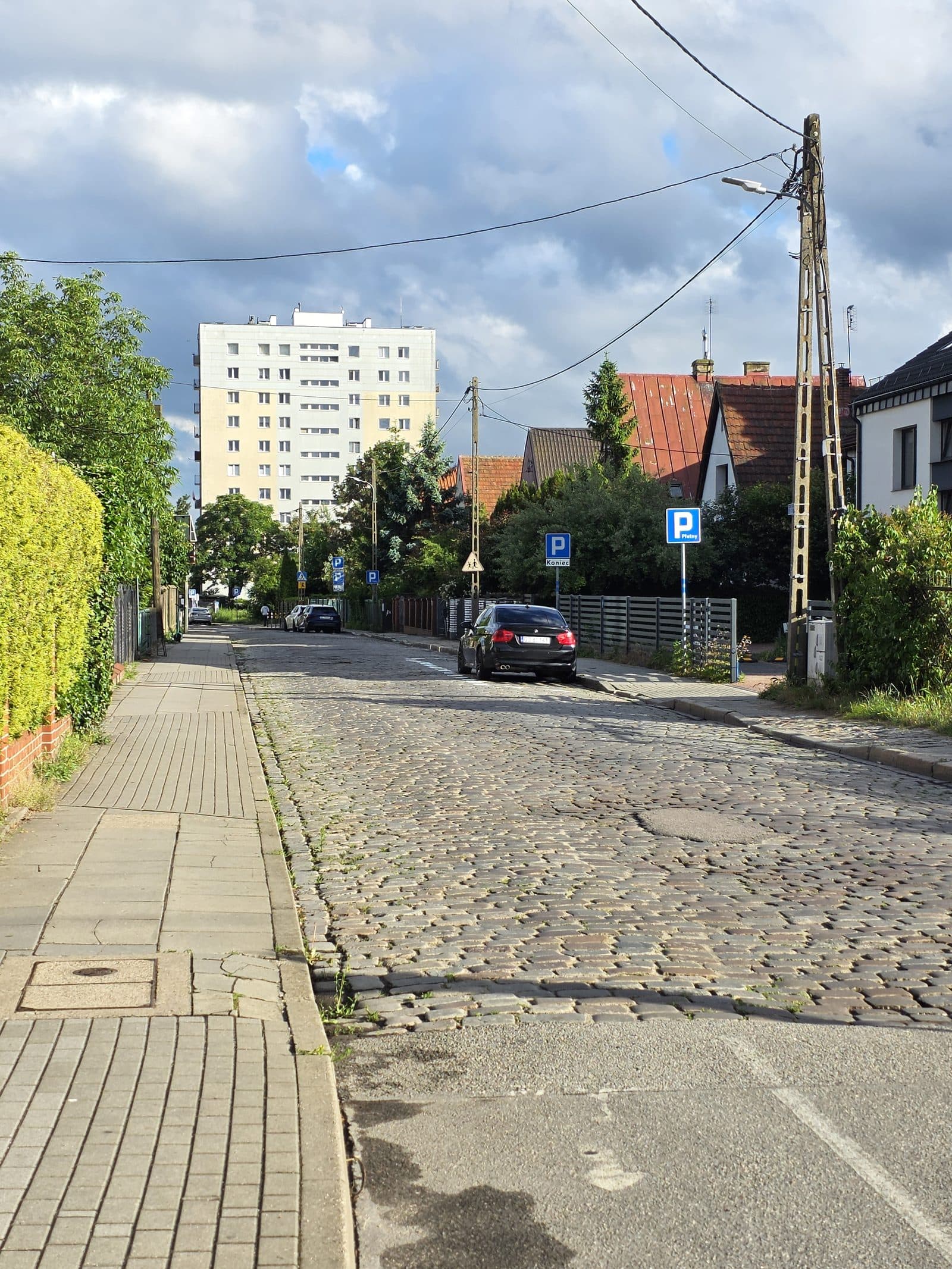 Brukowana nawierzchnia (kocie łby) i strefa płatnego parkowania w okolicy skrzyżowania