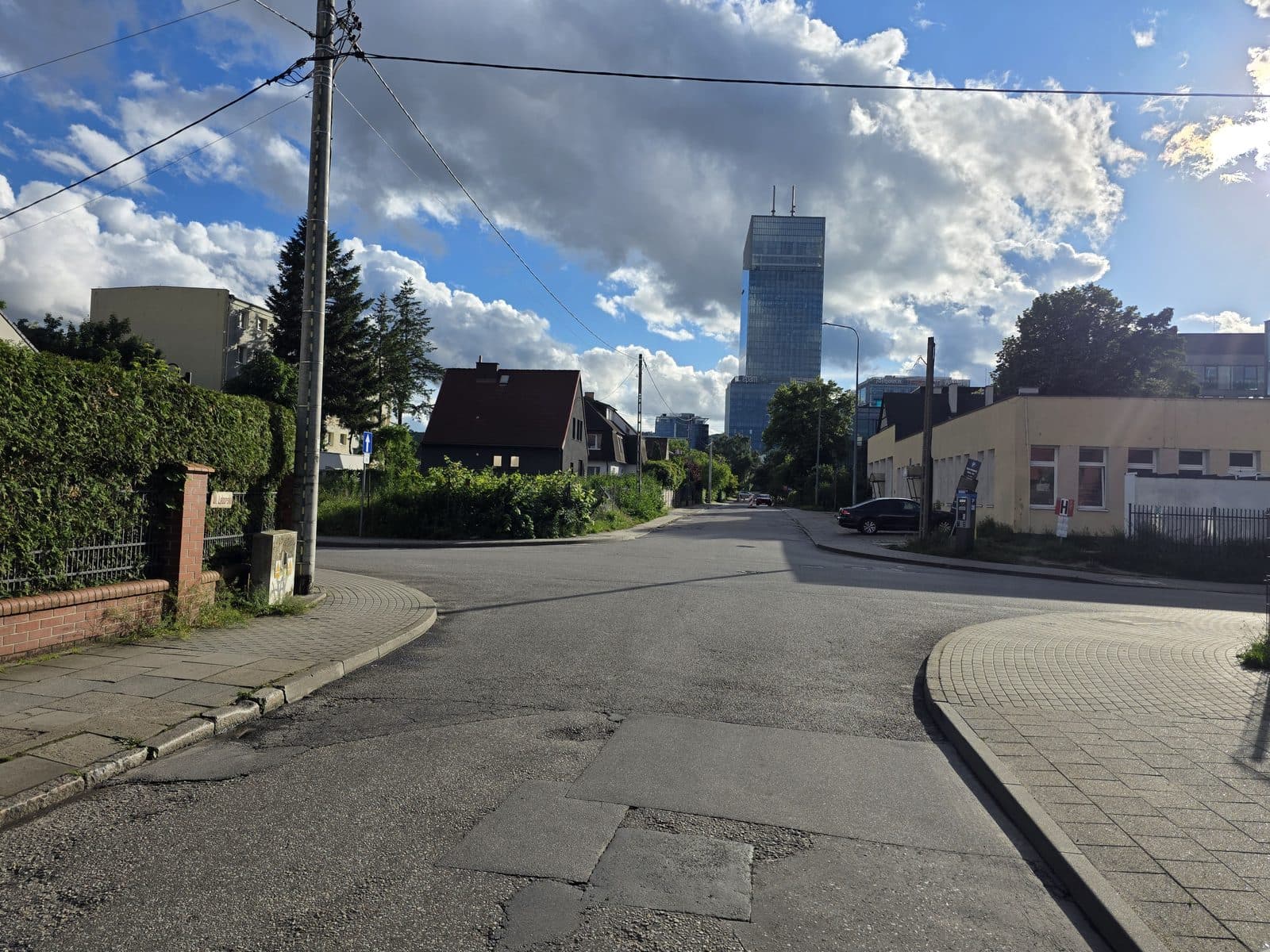 Załatana nawierzchnia jezdni przy ul. Lęborskiej, w tle wieżowiec Olivia